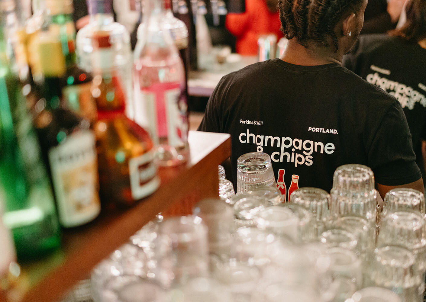 Bar scene with drinks and person wearing champagne & chips shirt.