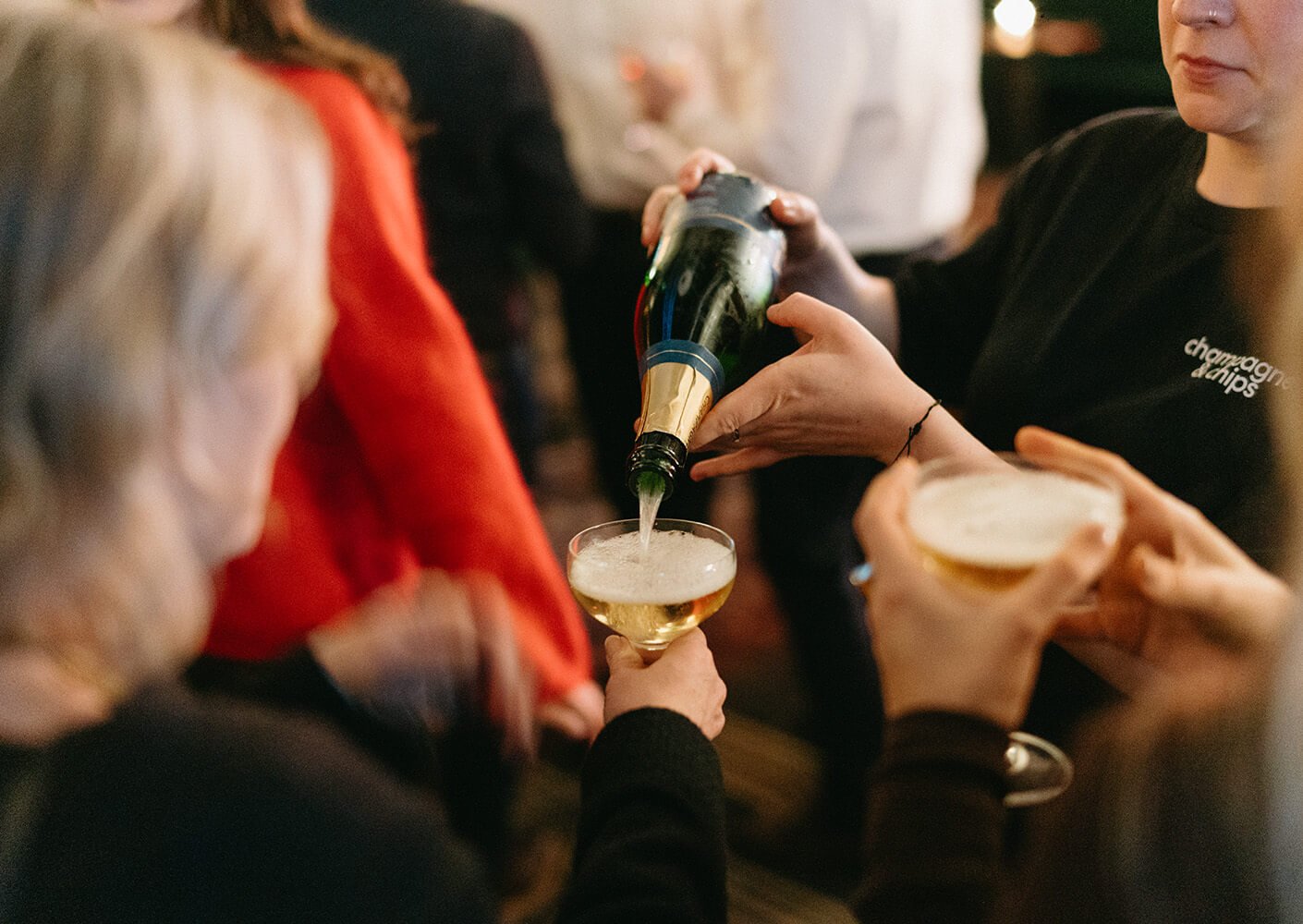 Pouring champagne at a lively party gathering.