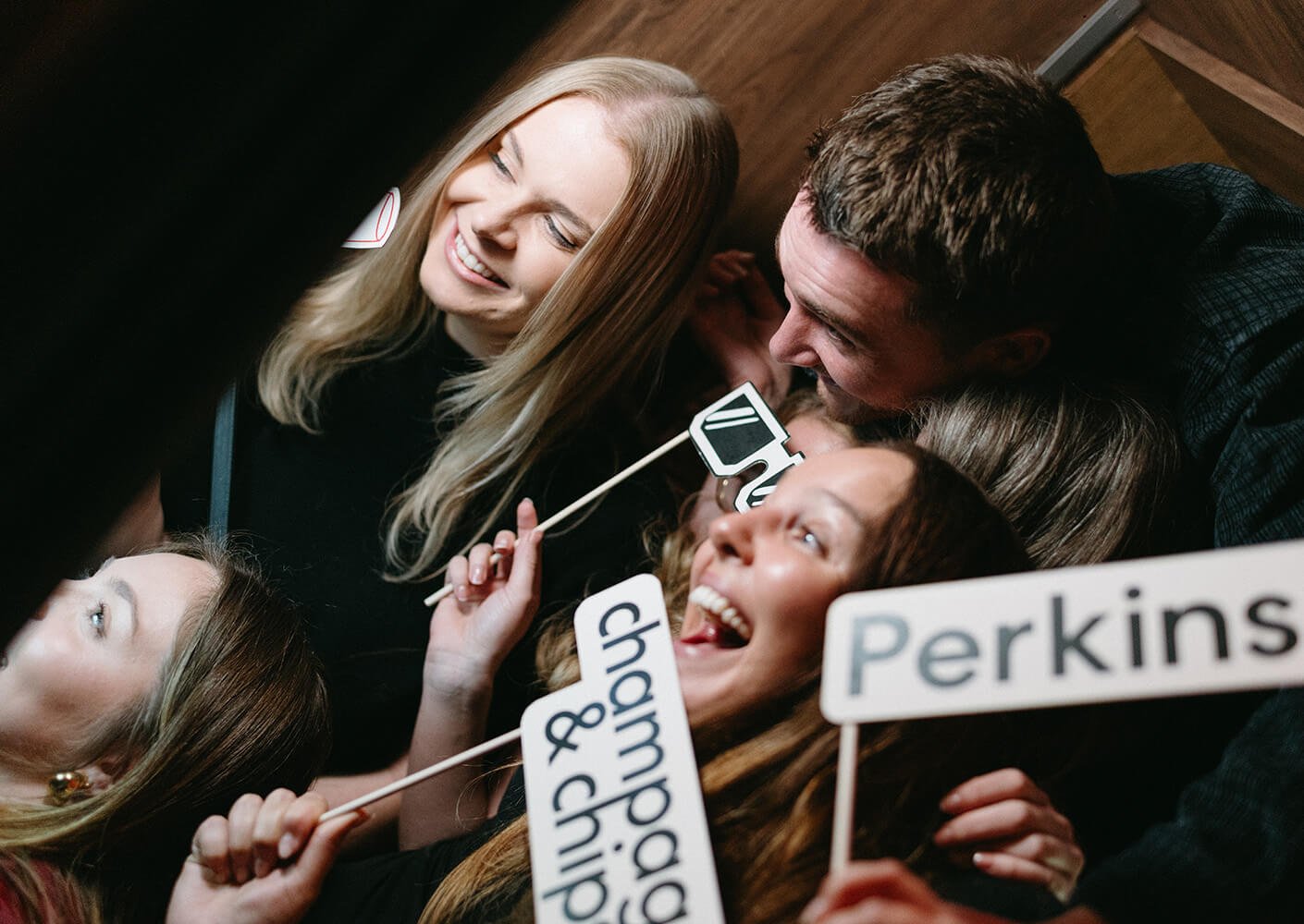 Group of friends having fun with party props in a photo booth.