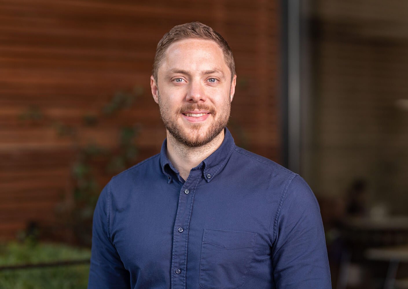 Man in blue shirt smiling with blurred background.
