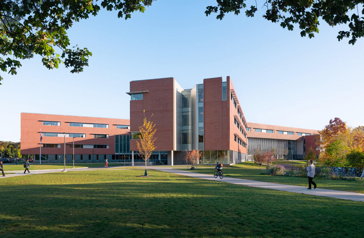 Modern brick school building surrounded by greenery and pathways in sunny weather.