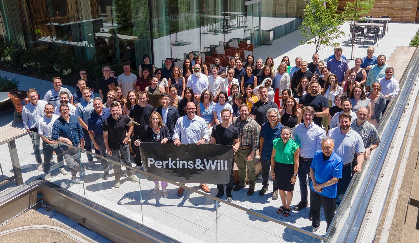 Group photo of Perkins&Will boston studio team members outside their office in a modern setting.