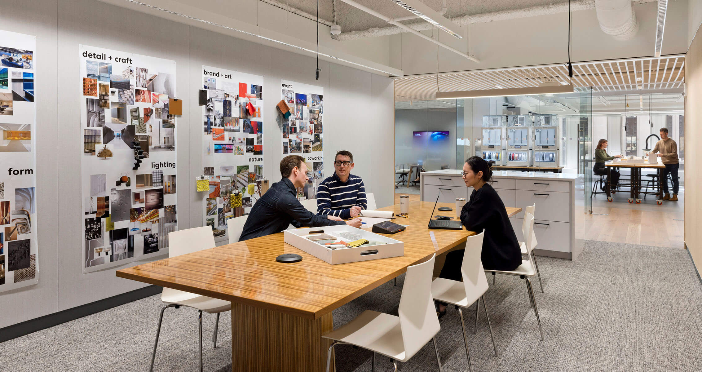 Three professionals collaborating in a modern office with design boards.