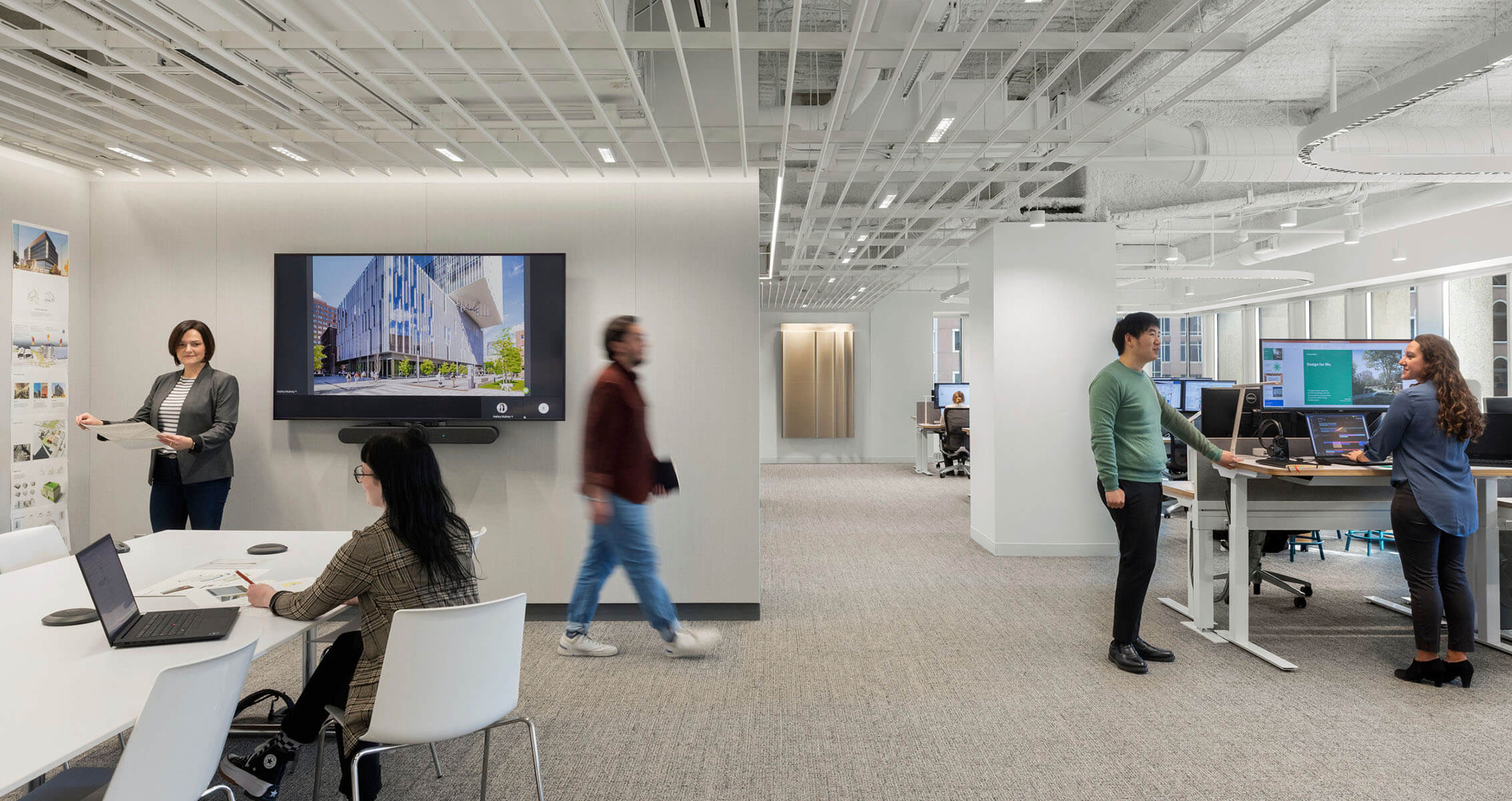 Modern office space with team collaboration, showcasing digital presentations and discussions.