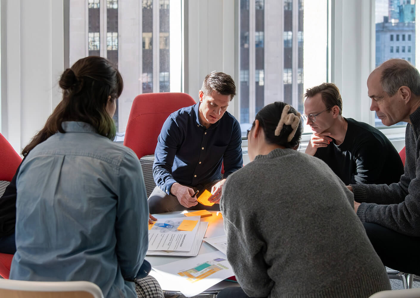Team collaborating in a bright office, discussing project materials and ideas.