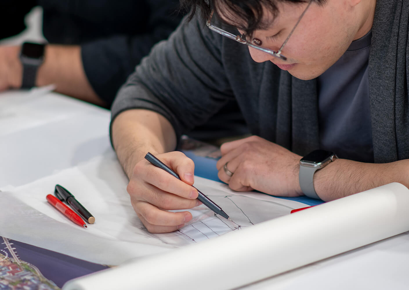 A person sketches plans on paper during a collaborative design session.