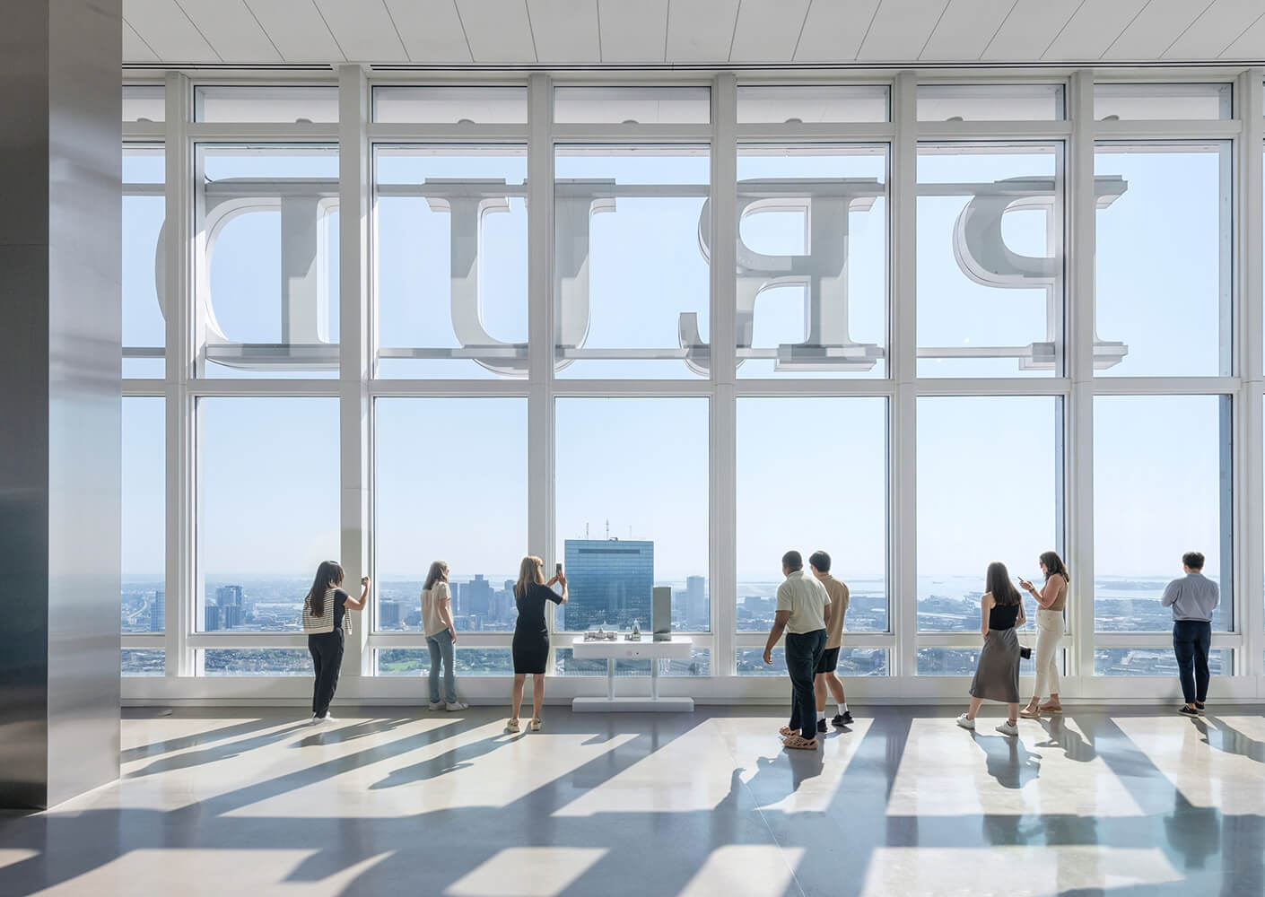 Visitors admiring the city view from a modern observation deck with large windows.