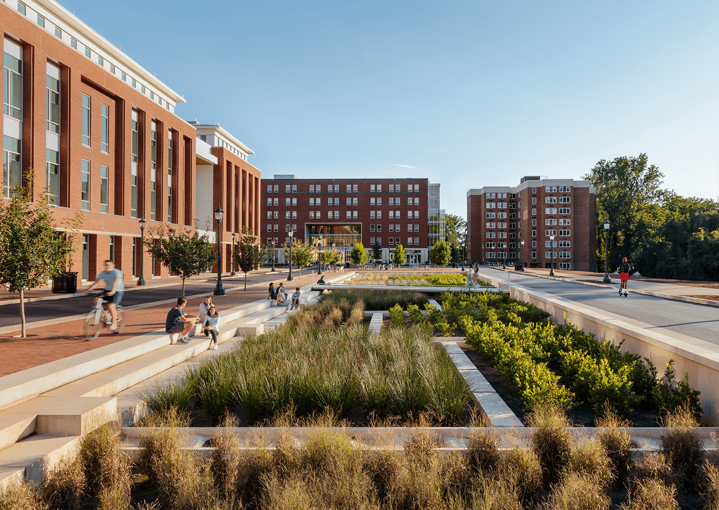 Modern university campus with students relaxing, biking, and enjoying landscaped pathways.