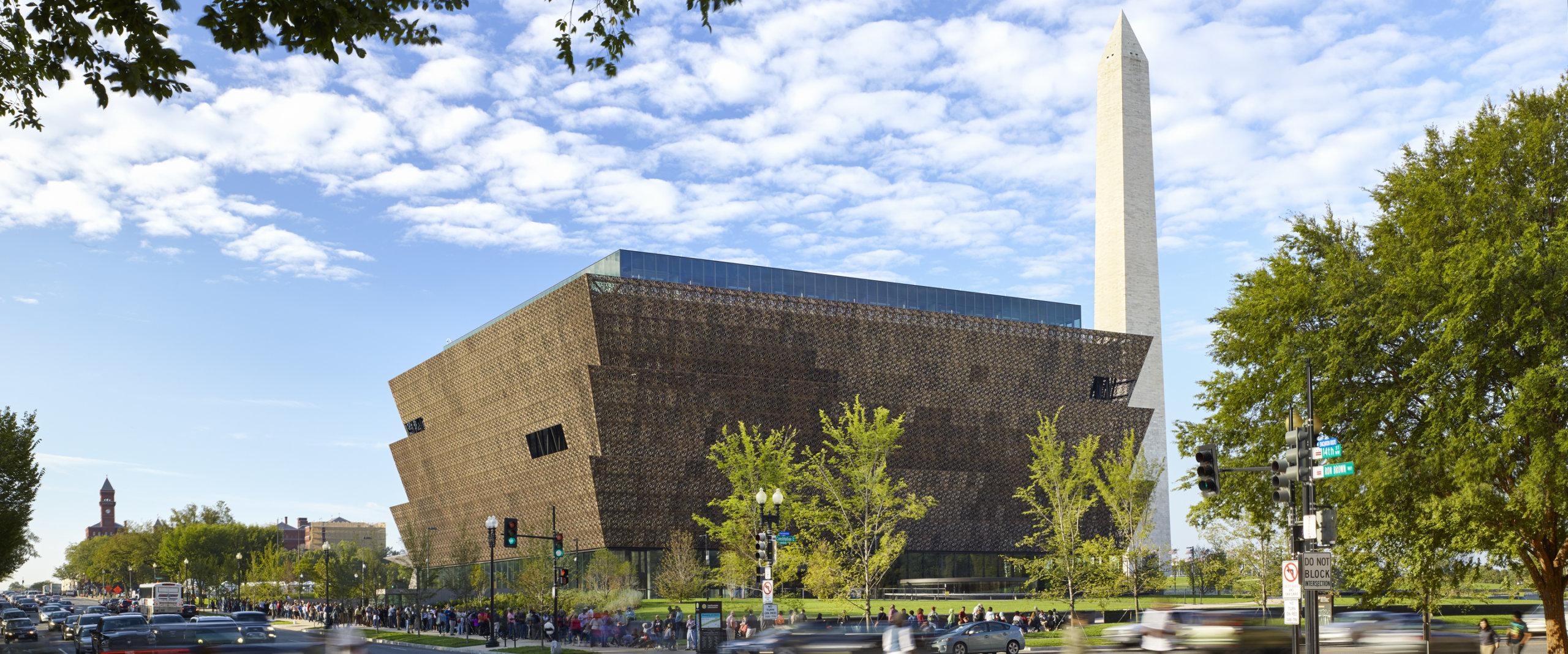 Exterior photo of the NMAAHC with the Washington Monument in the background