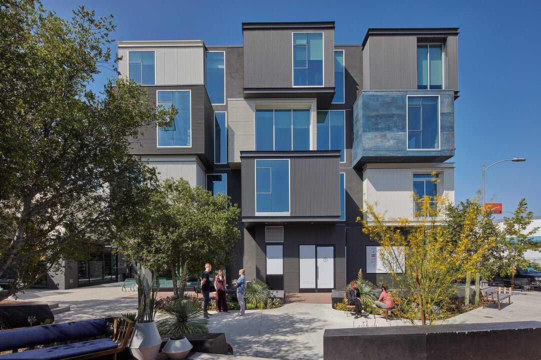 Modern apartments with geometric design and trees in the foreground.