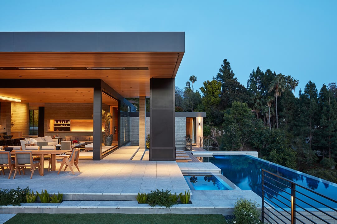 Modern luxury home with open patio and pool at twilight.