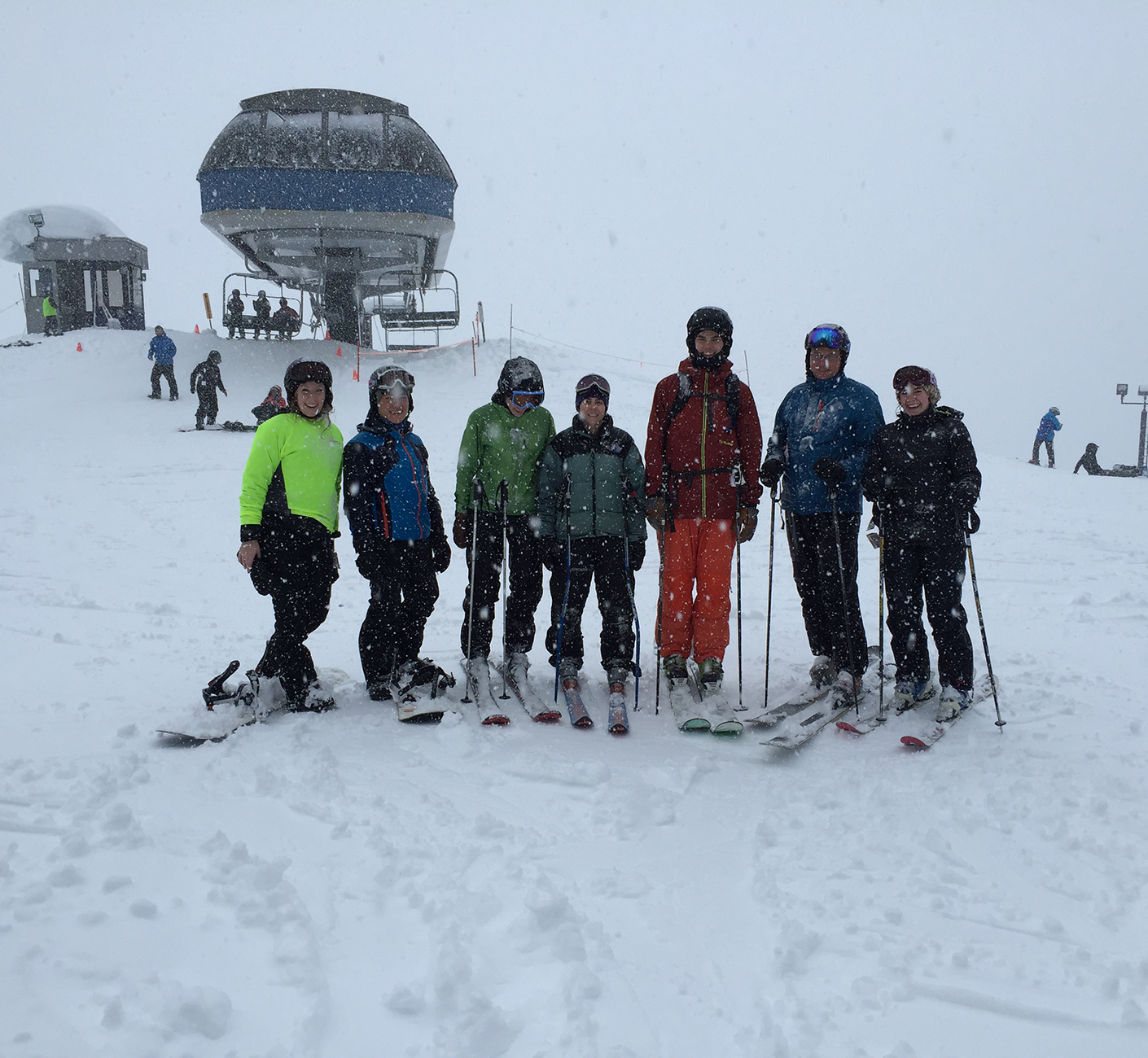 People on skis and snowboards on the top of a snowy mountain