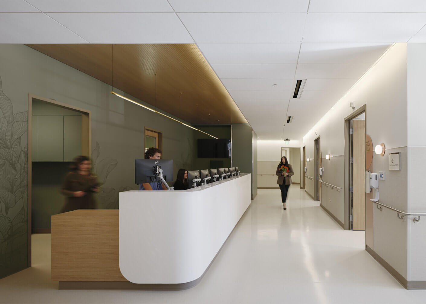 Modern hospital reception area with staff and visitor.
