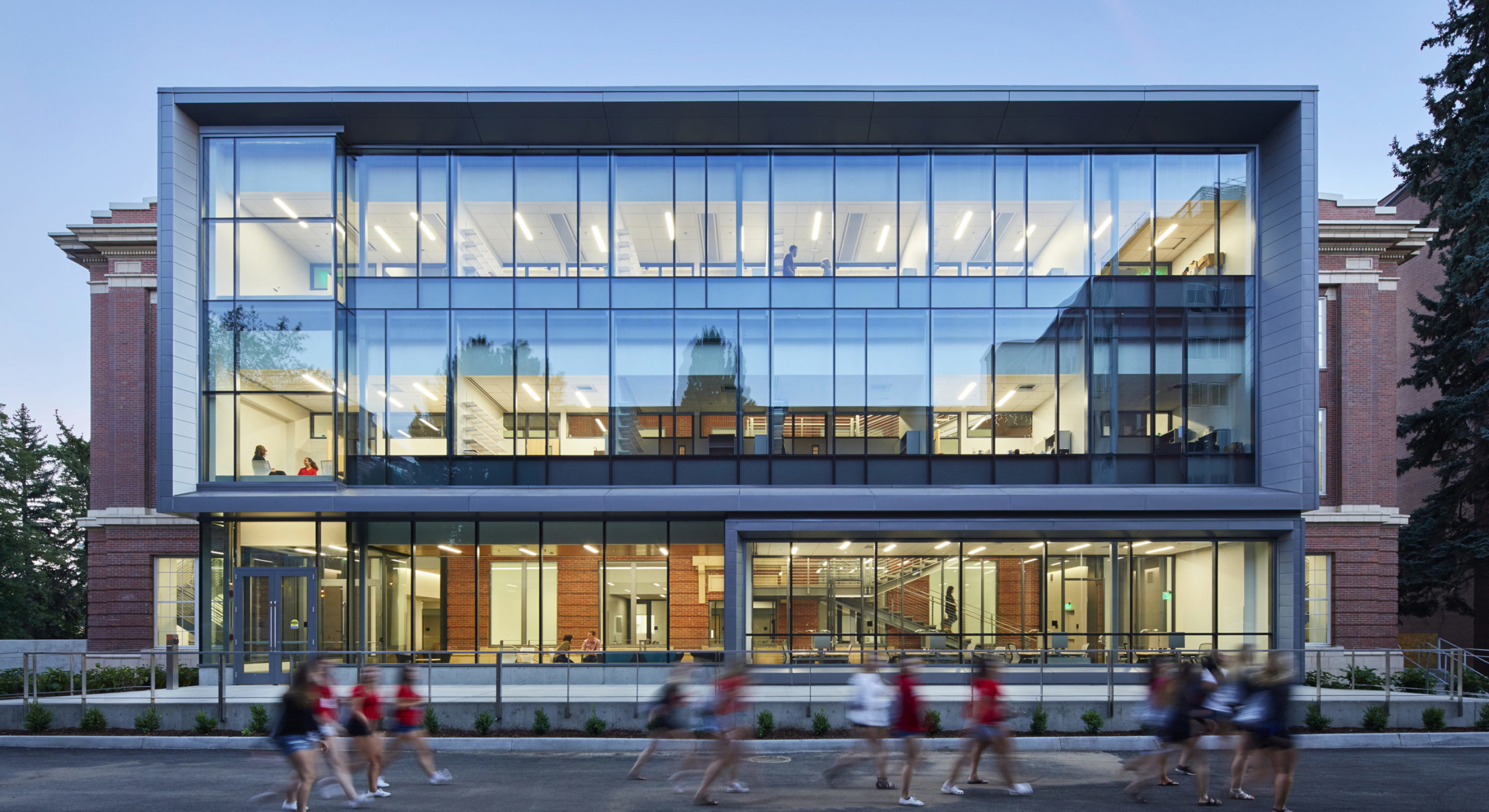 North facade of WSU Troy Hall with glass box atrium and students walking by in the foreground.