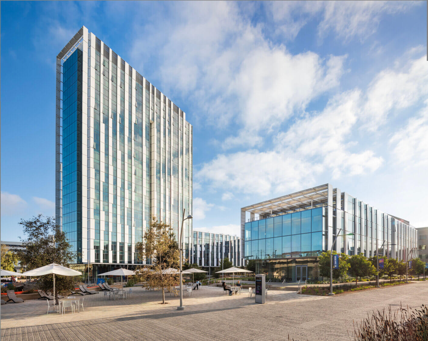 Modern glass office buildings under a blue sky in a cityscape setting.