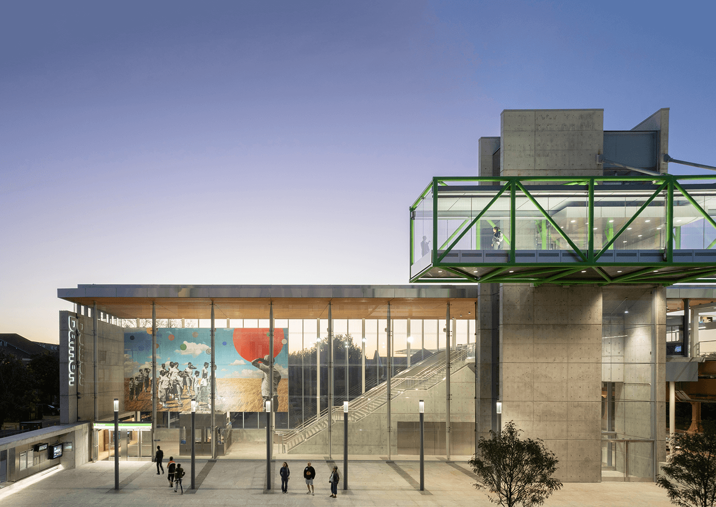 Modern building exterior with glass walkway and evening sky.