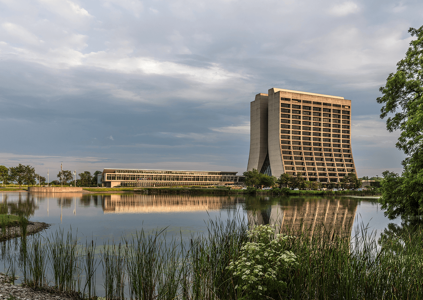 Modern lakeside building with unique architecture against a cloudy sky.