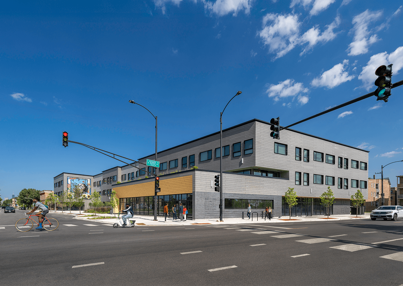 Modern urban building with people crossing intersection under clear blue skies.