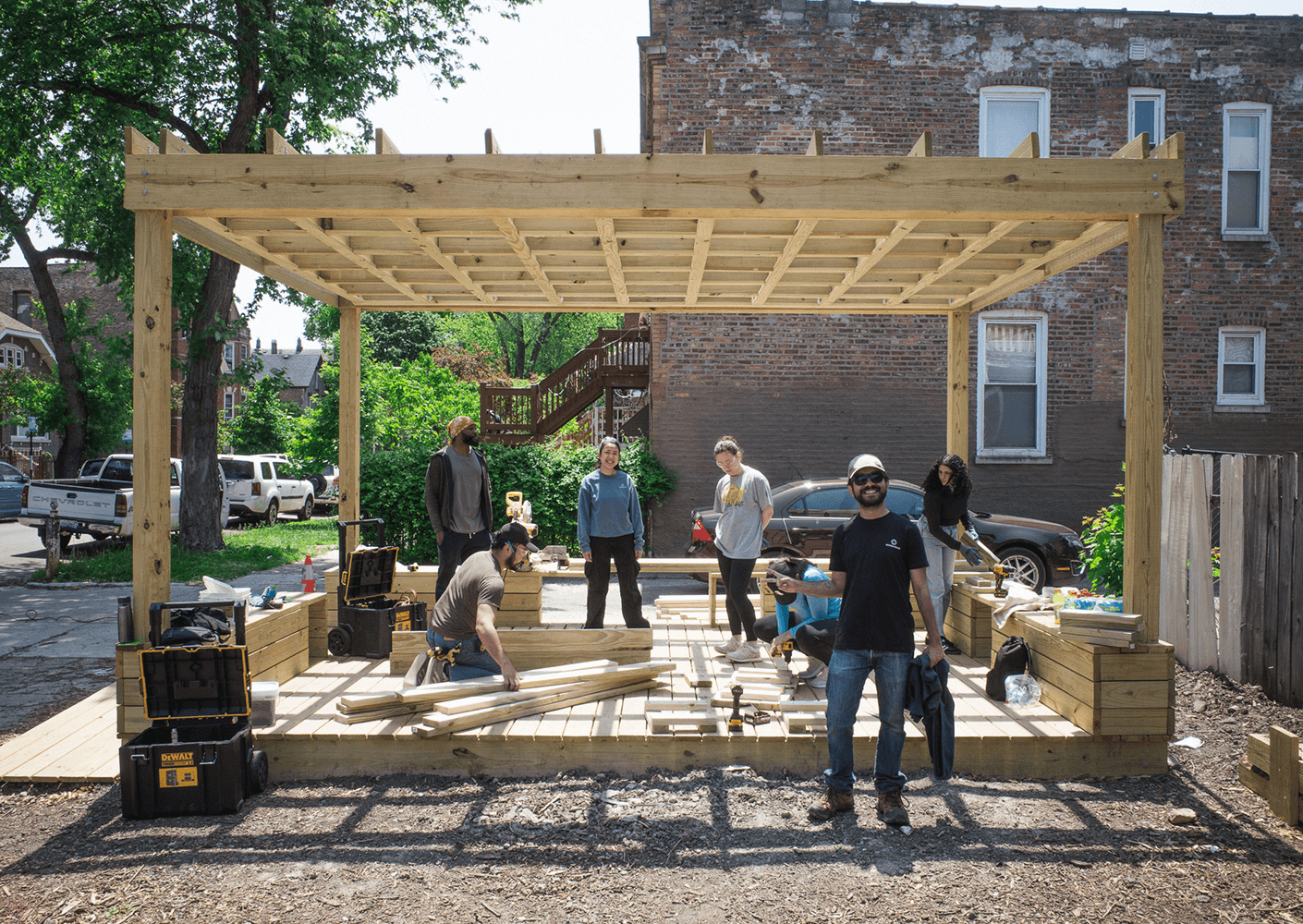 Group assembling wooden structure outdoors in urban setting.