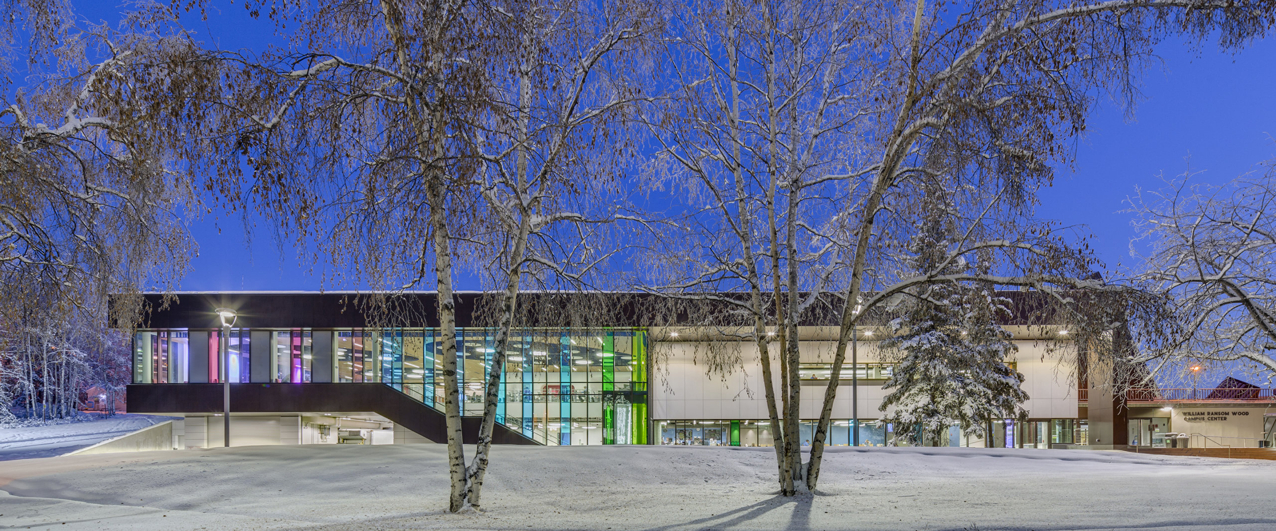 University of Alaska Fairbanks Wood Center at dusk with snow on the ground and trees