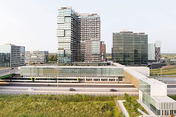 Modern urban skyline with glass buildings and a highway in the foreground.