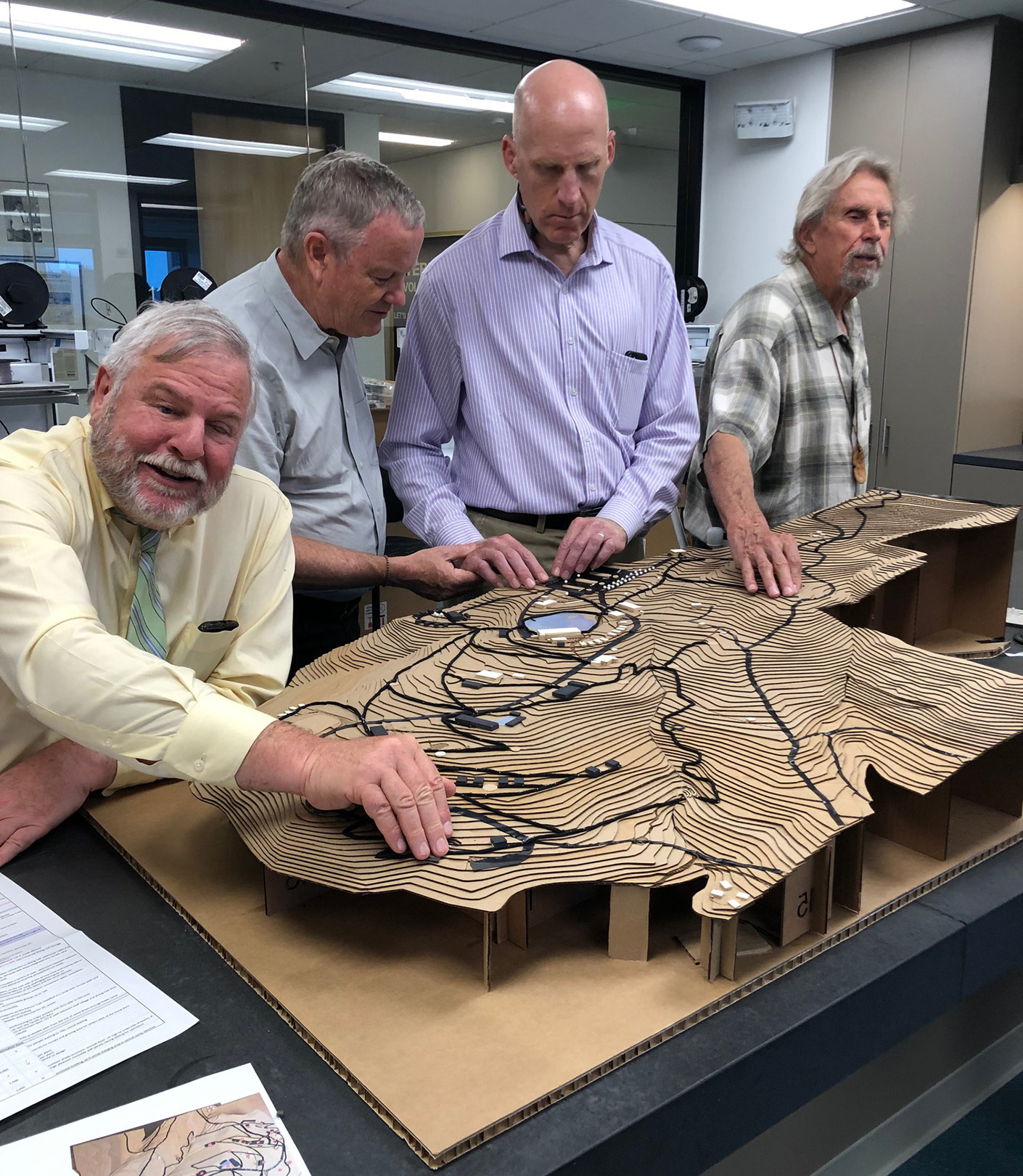 Demonstration of the tactile model. Four men feel the raised textures on the model.