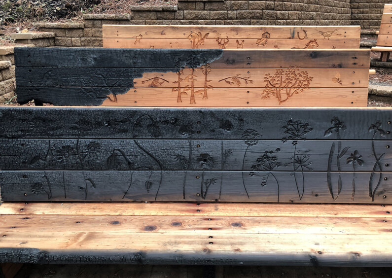 Benches with floral engravings. They are blackend by the fire in some sections.