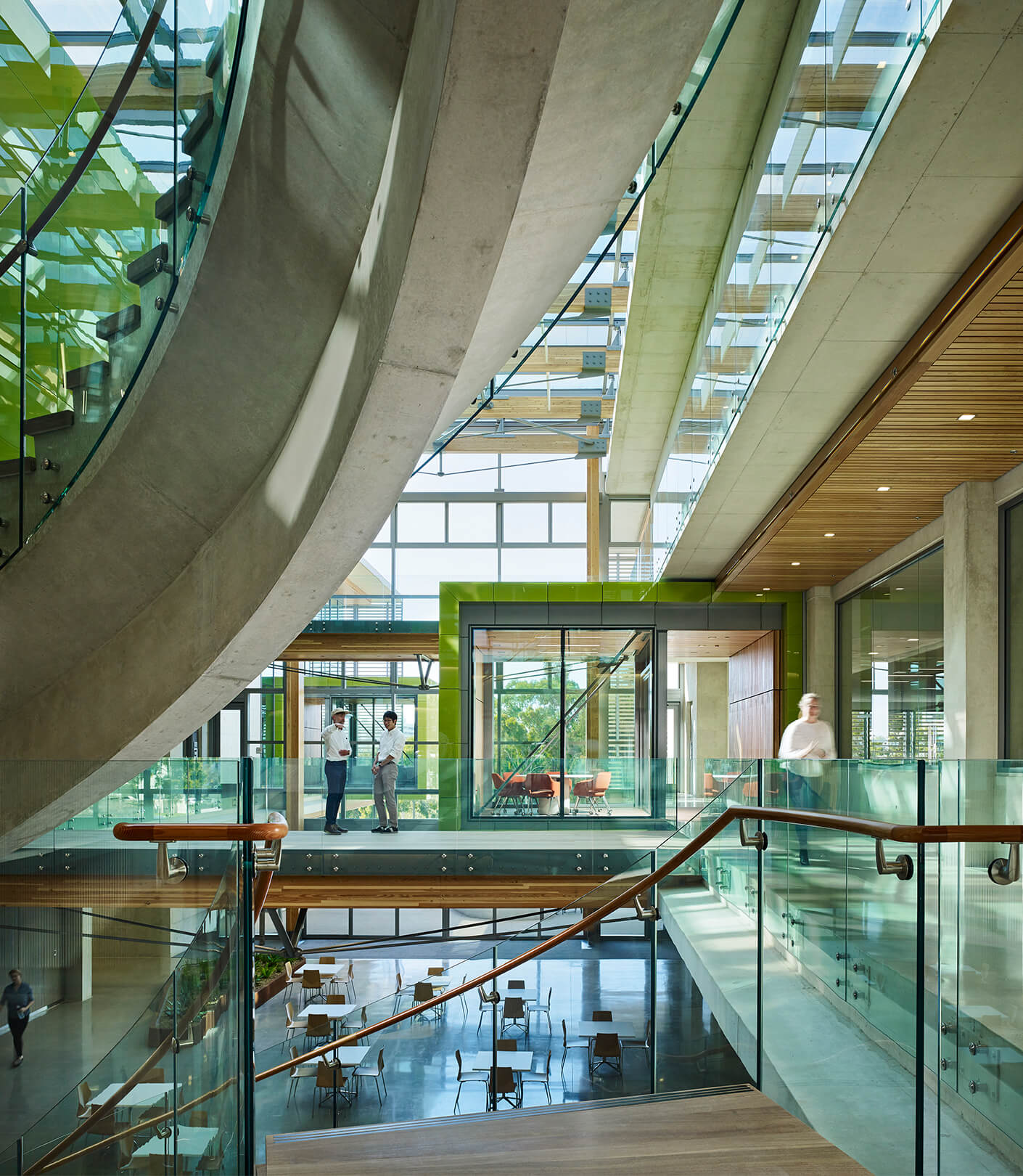 Central atrium with winding concrete stairs and green meeting pods
