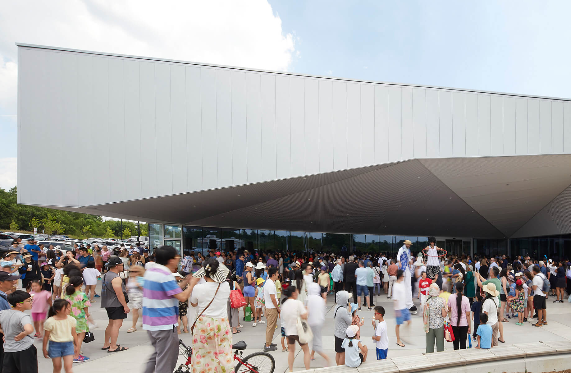 Crowd gathered outside modern building on a sunny day.