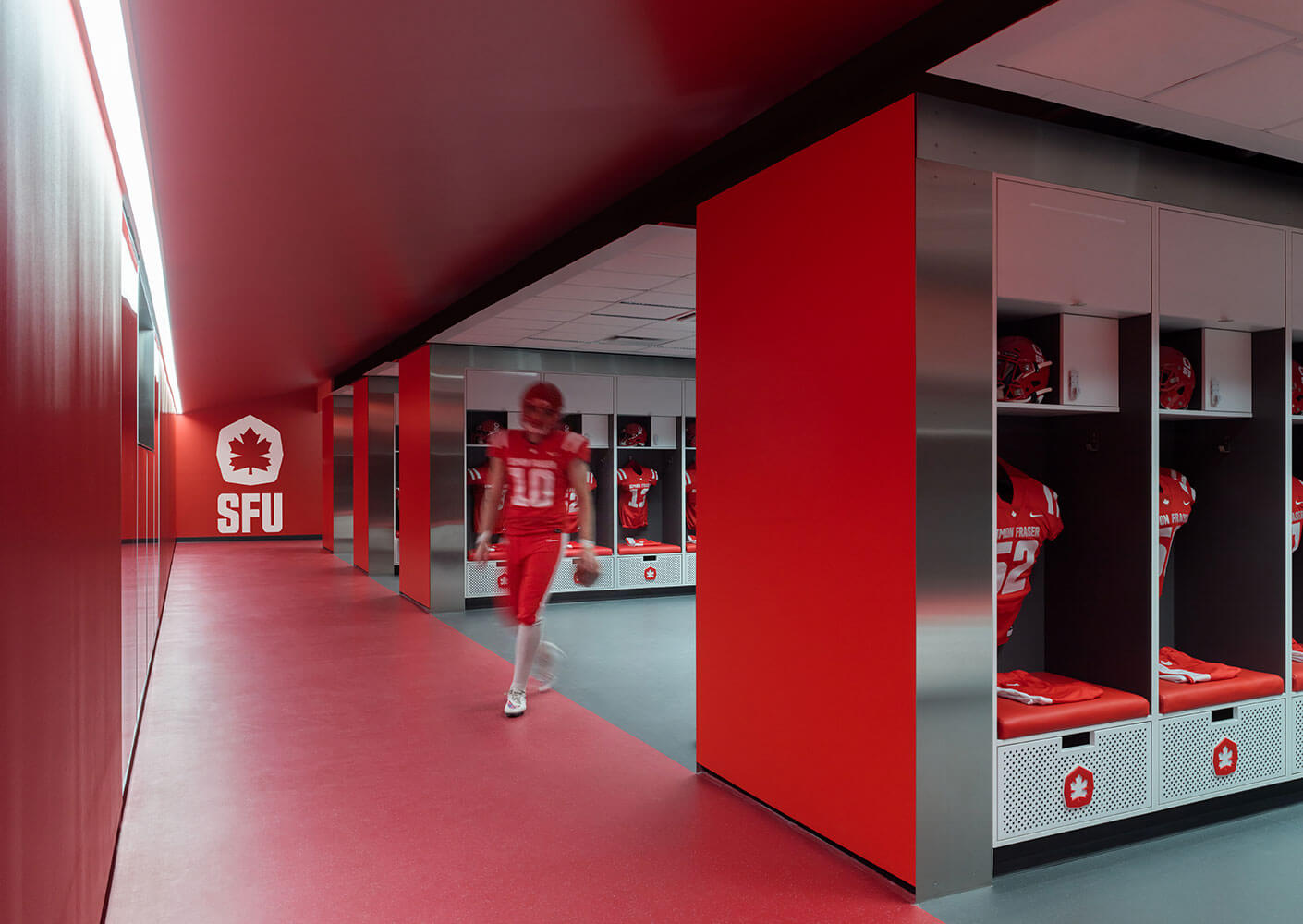 Player walking out from central bay of lockers in the football locker room at SFU stadium.