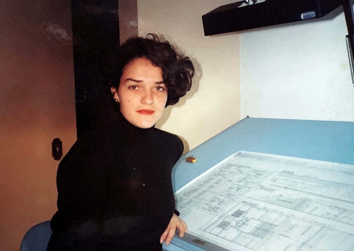 Laura sits at a drafting table as a young designer