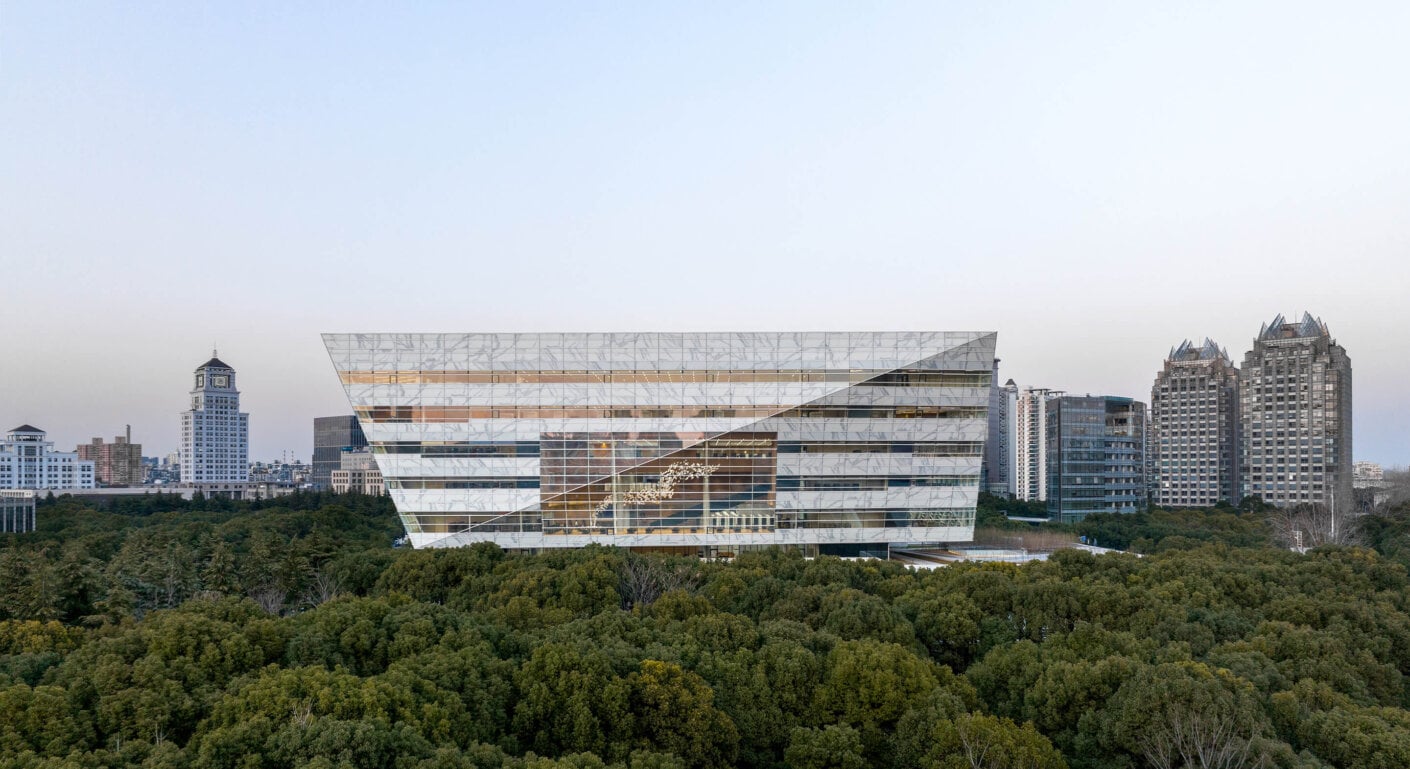 Modern architectural library surrounded by greenery and urban skyline.