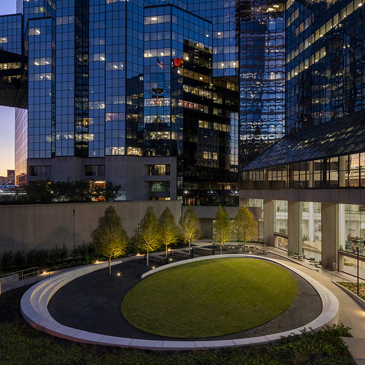 Looking into the lighted sculptured seating wall and elliptical lawn of the Atlanta Financial Center courtyard at night