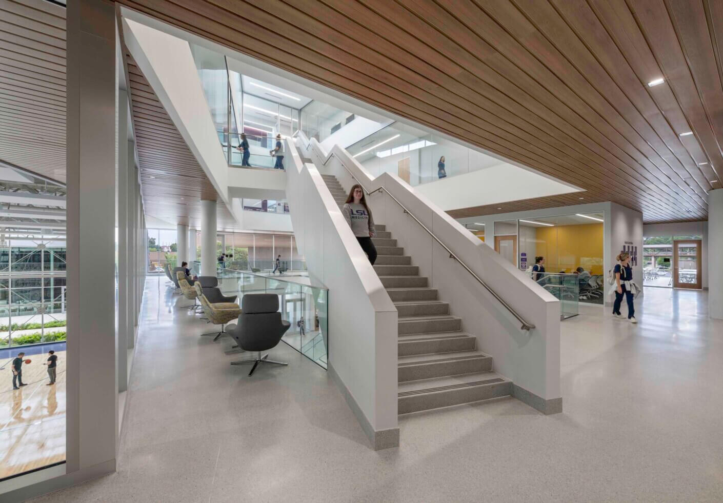 Modern atrium with staircase, people walking, and visibility to multiple floors at once.