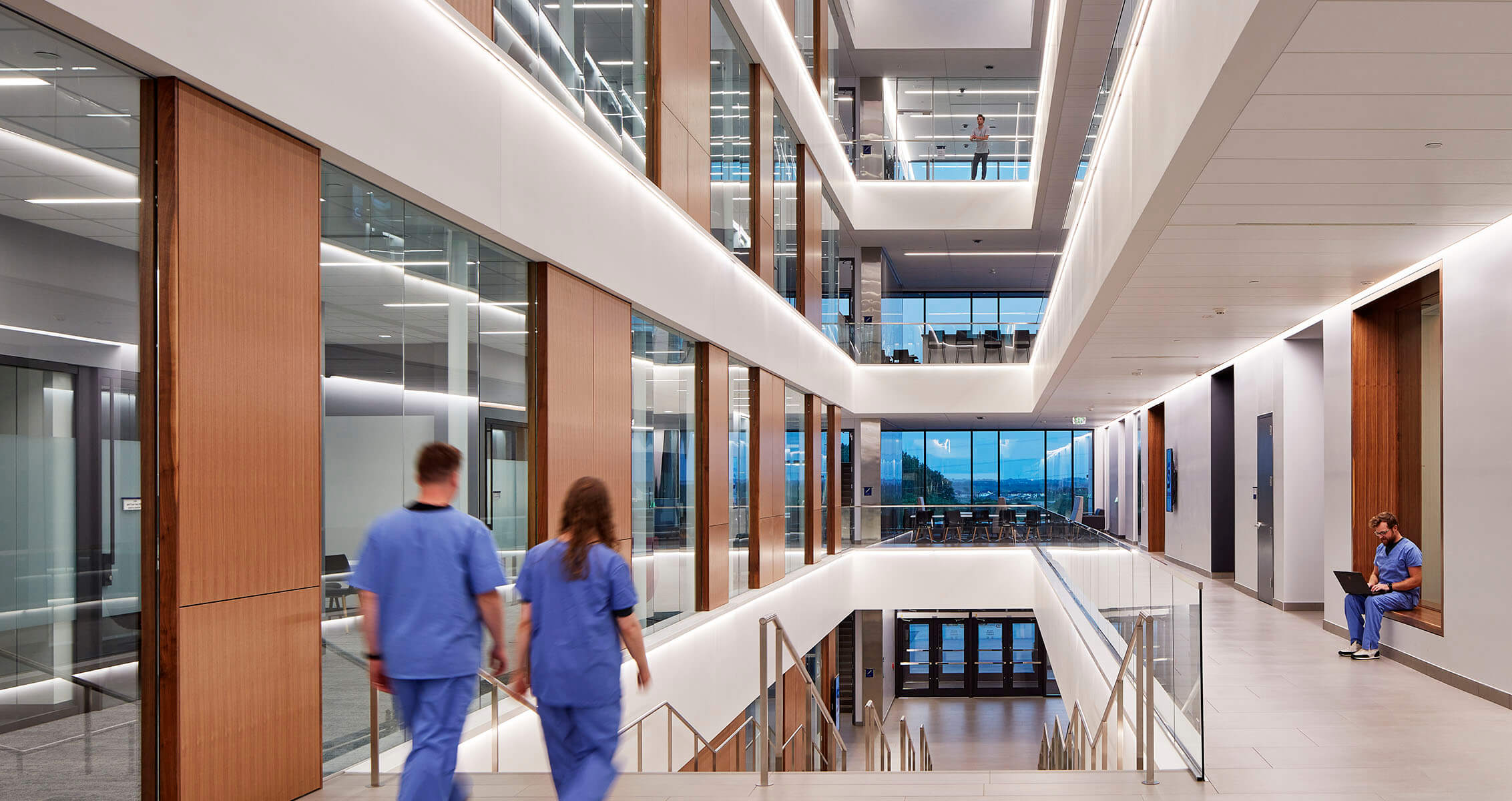 Photo of medical students approaching stairs in atrium of a health sciences building