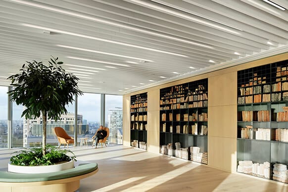 Modern office space with bookshelves, large windows, and indoor plants for a cozy atmosphere.