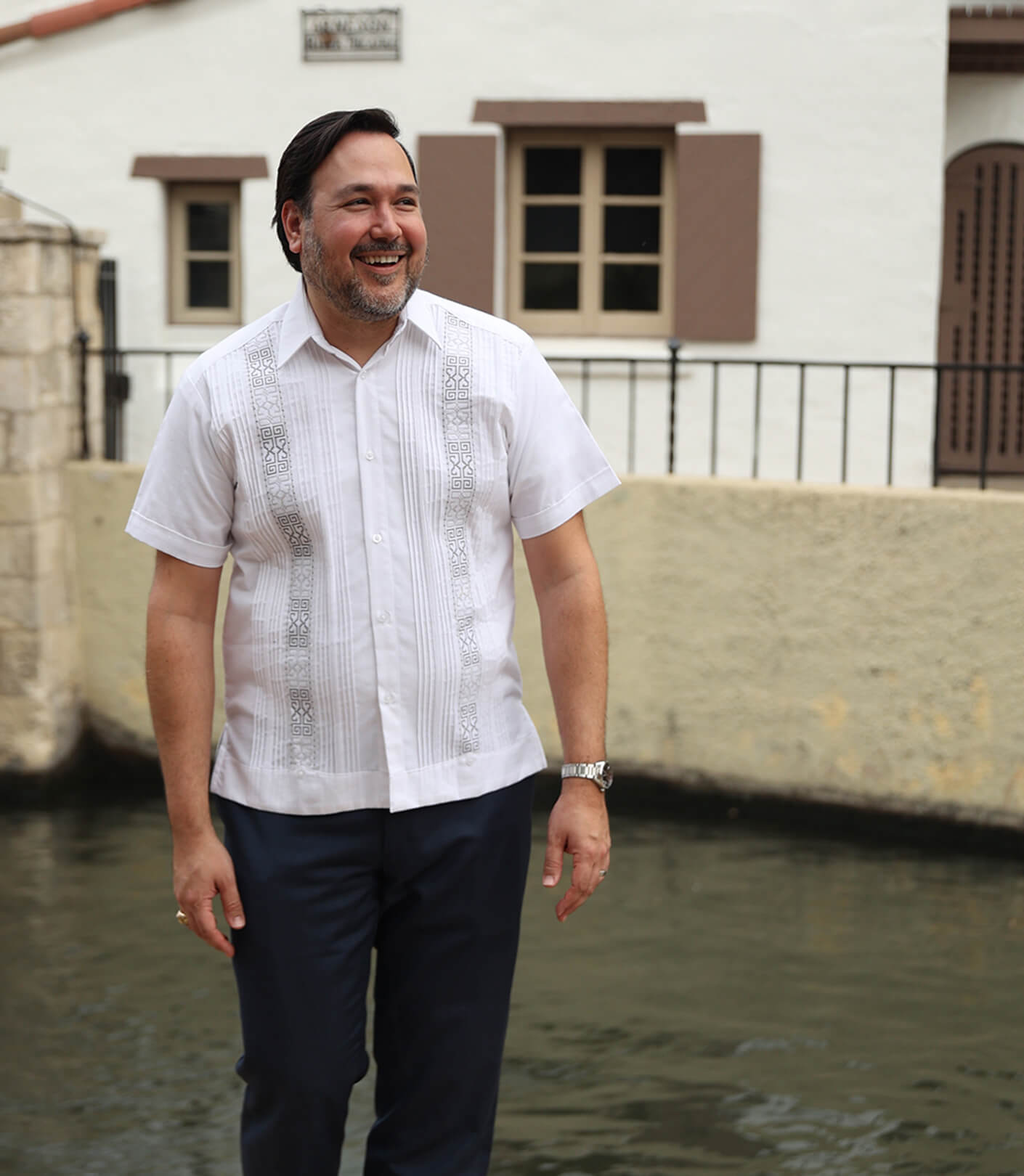 Omar stands smiling near the San Antonio river walk