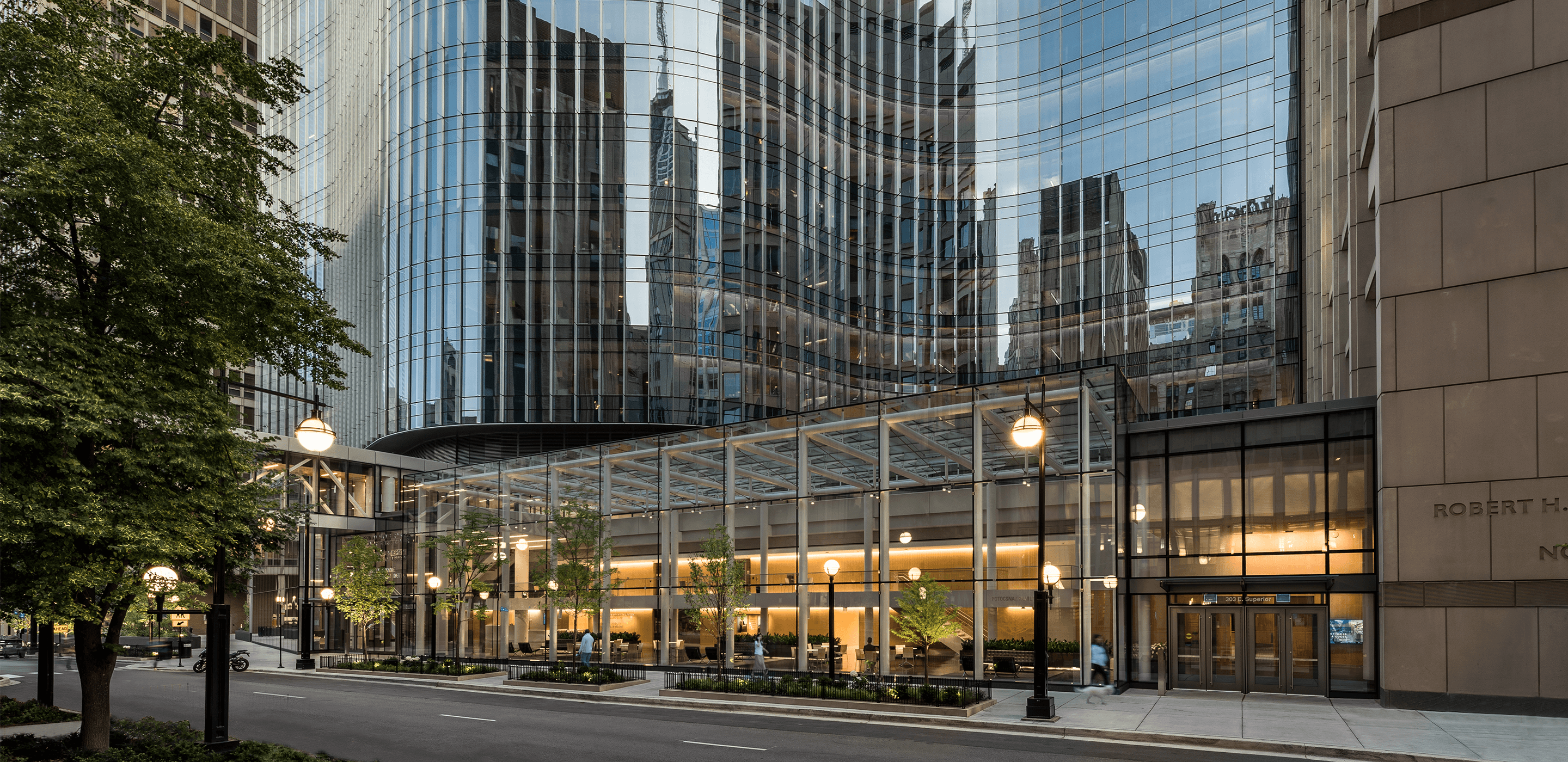 Photo of urban research lab in downtown Chicago. A ground-floor atrium is topped by a glass tower with an undulating façade.