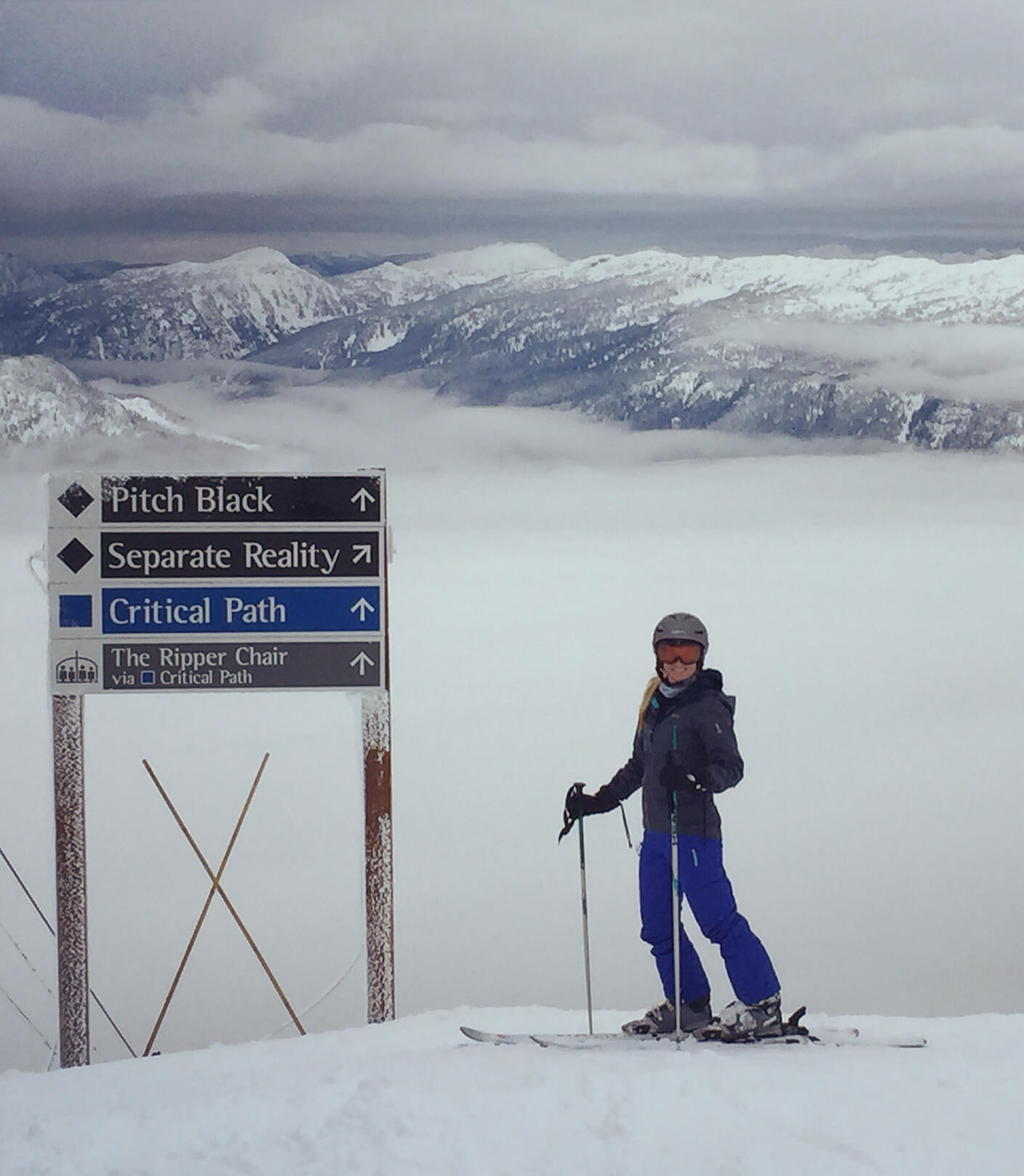 Sarah posing on skis at the top of a snowy mountain