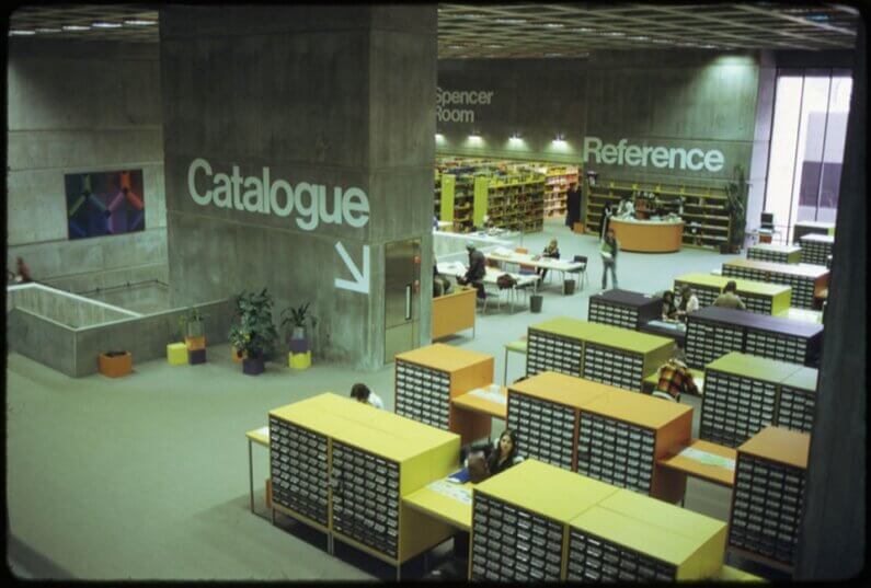 An old, film photo showing the original design of the atrium, with bookcases dispersed through the space
