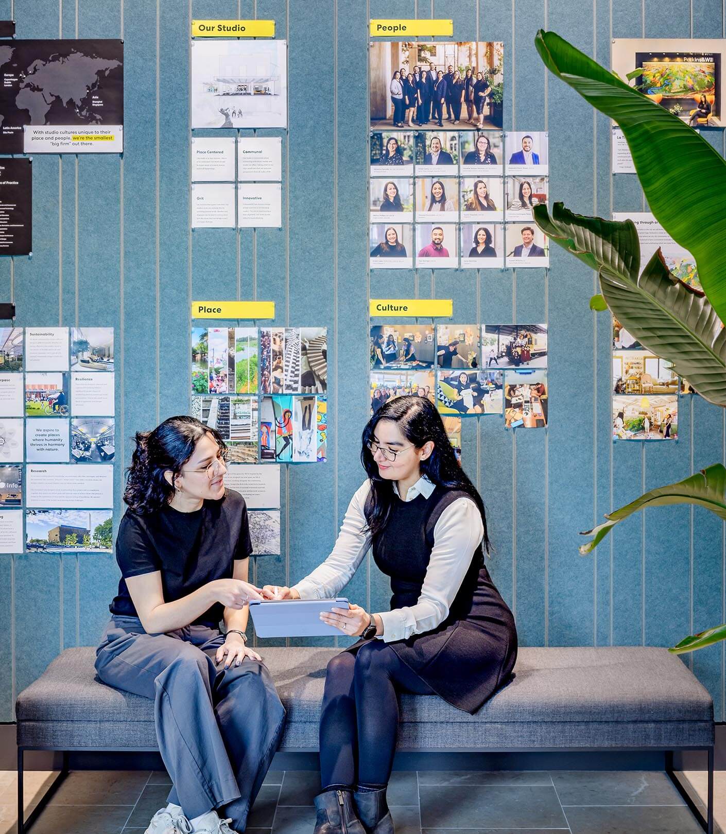 Adrianna sits next to a young designer in the San Antonio studio, discussing work in front of a gallery wall that tells the studio's story
