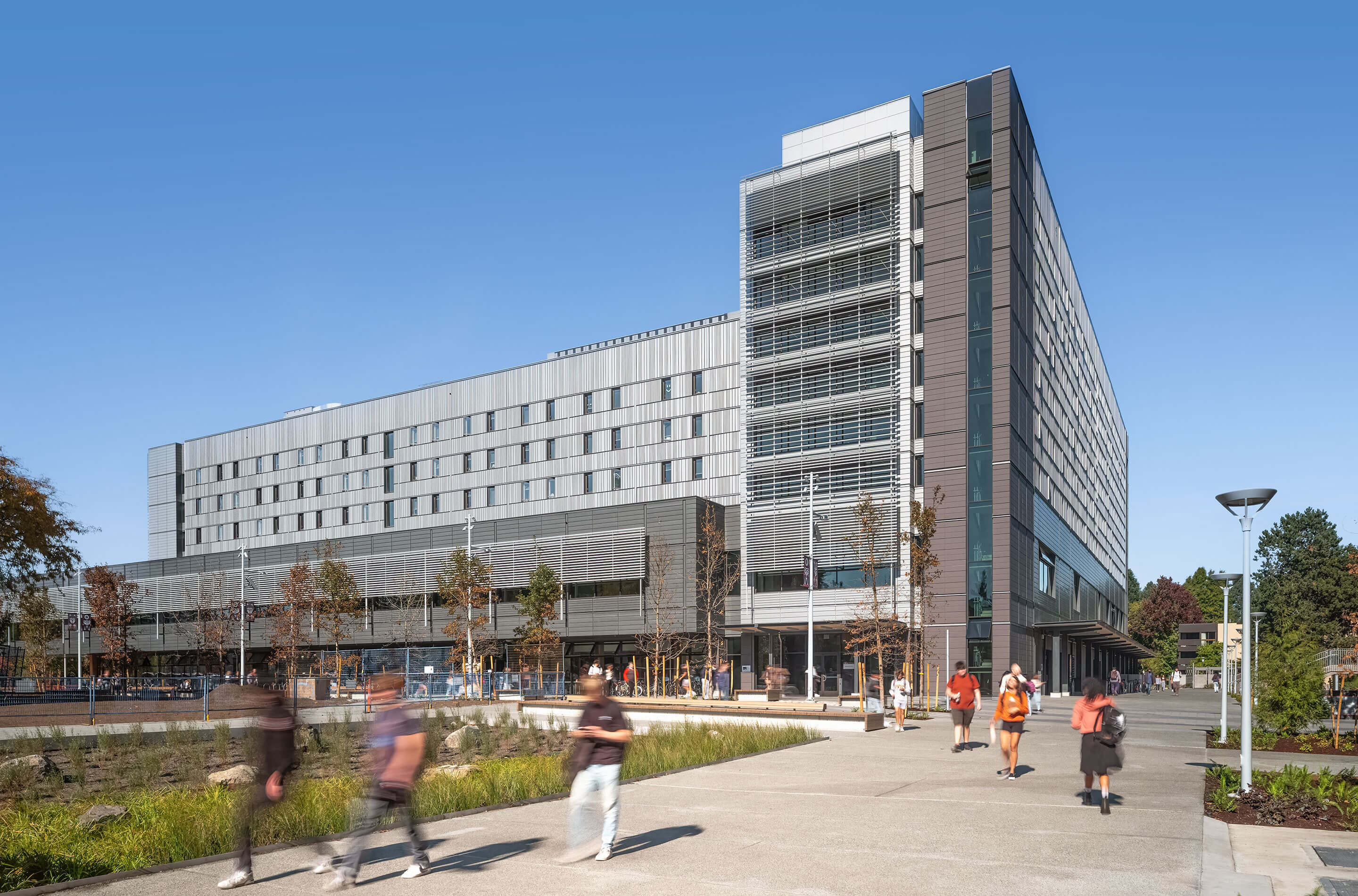 View of the residence entry of Cheko’nien House from the Precinct Greenway with students walking.