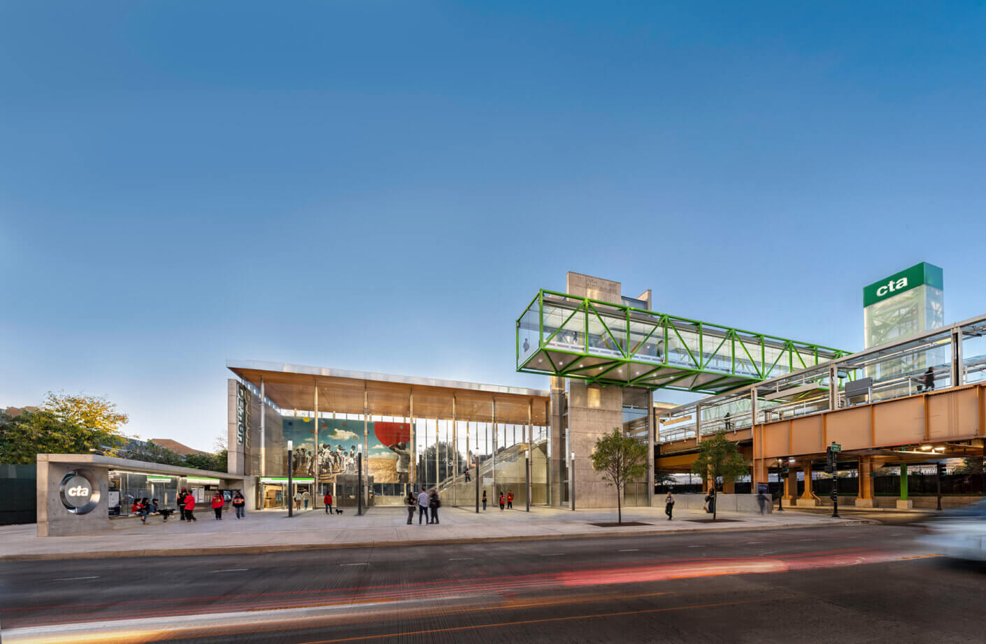Modern urban train station with glass architecture and people, under a clear blue sky.