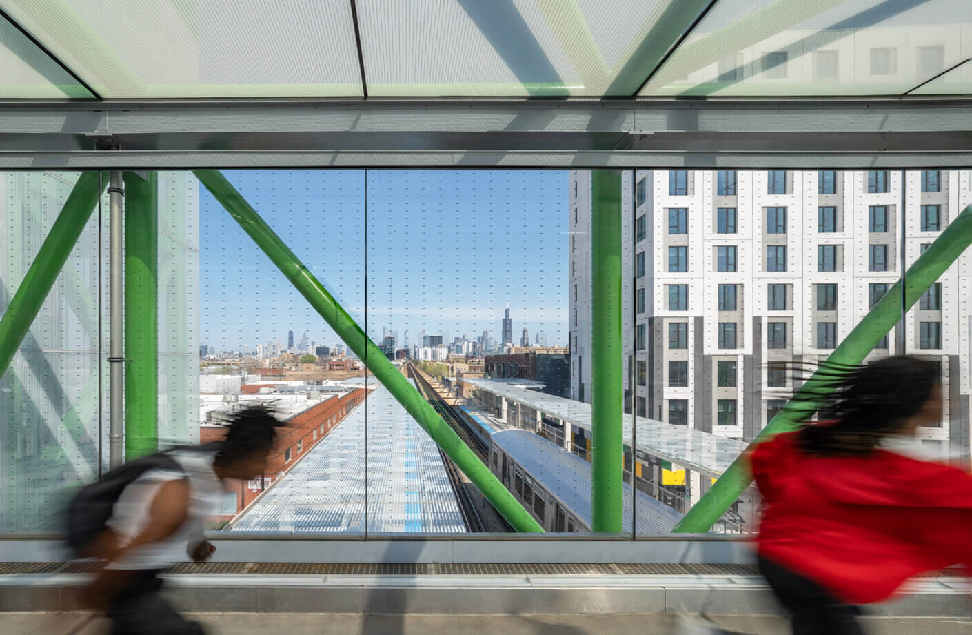 Kids running in a modern glass corridor with Chicago skyline in the background, featuring bright green beams.