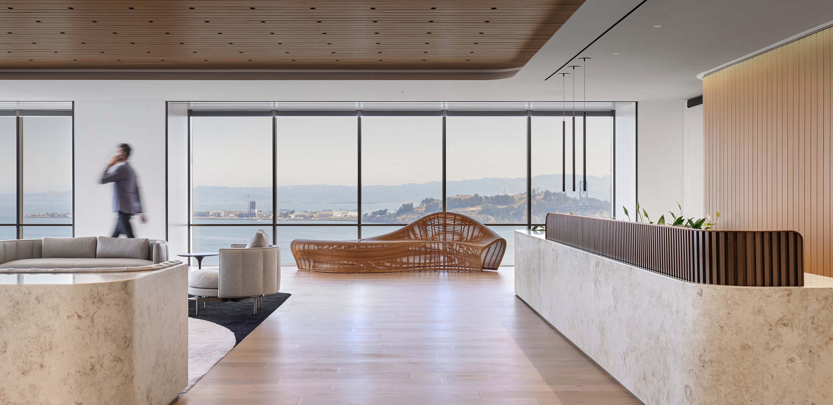 the reception area of an office, with a marble desk and woven chair overlooking the san francisco bay