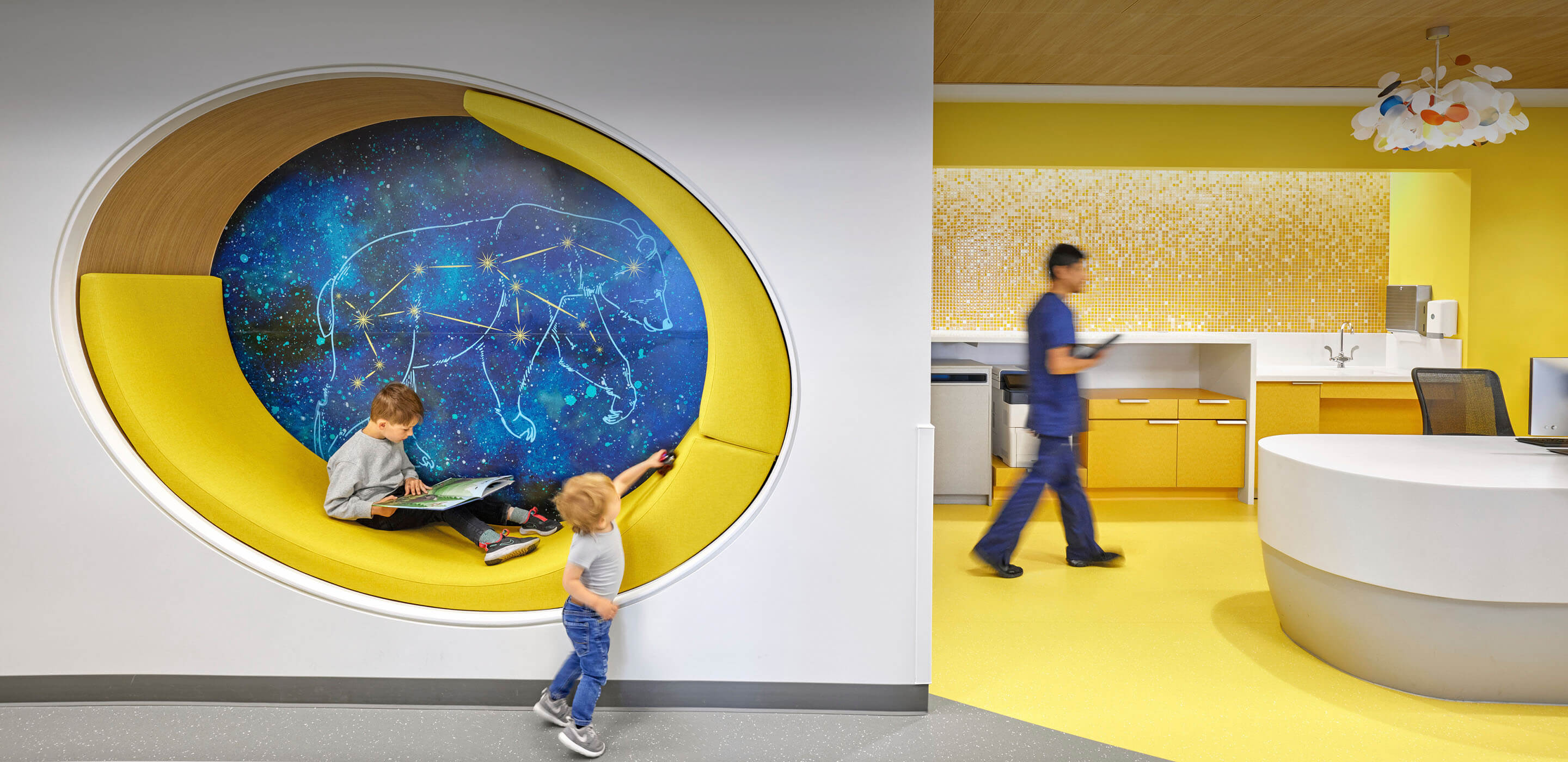 two children read and play on a cushioned wall seat