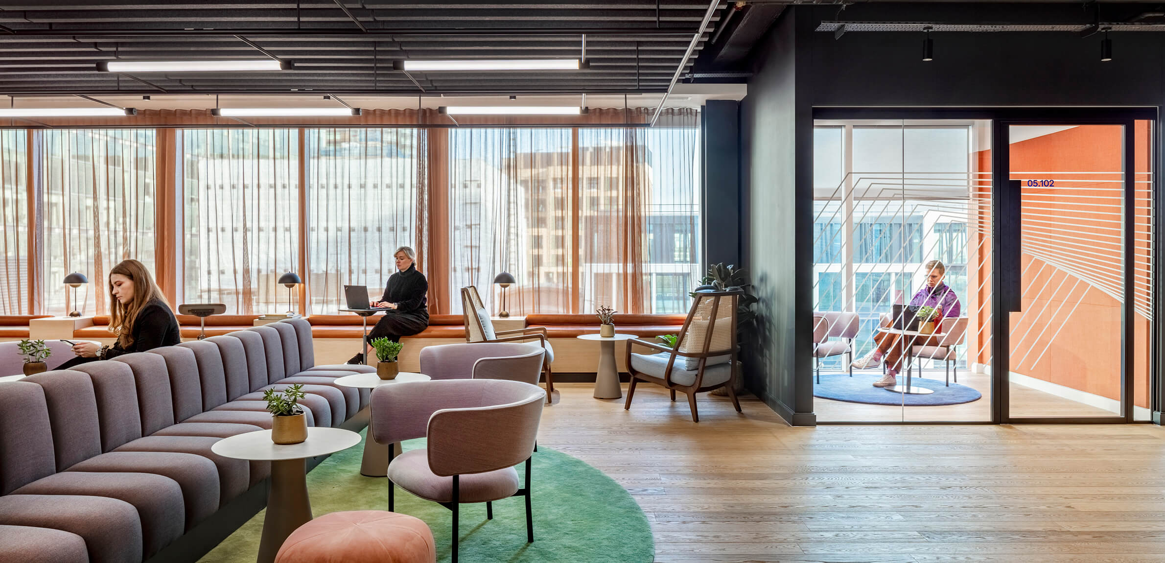 An open office area with people using varous seating and working spaces.