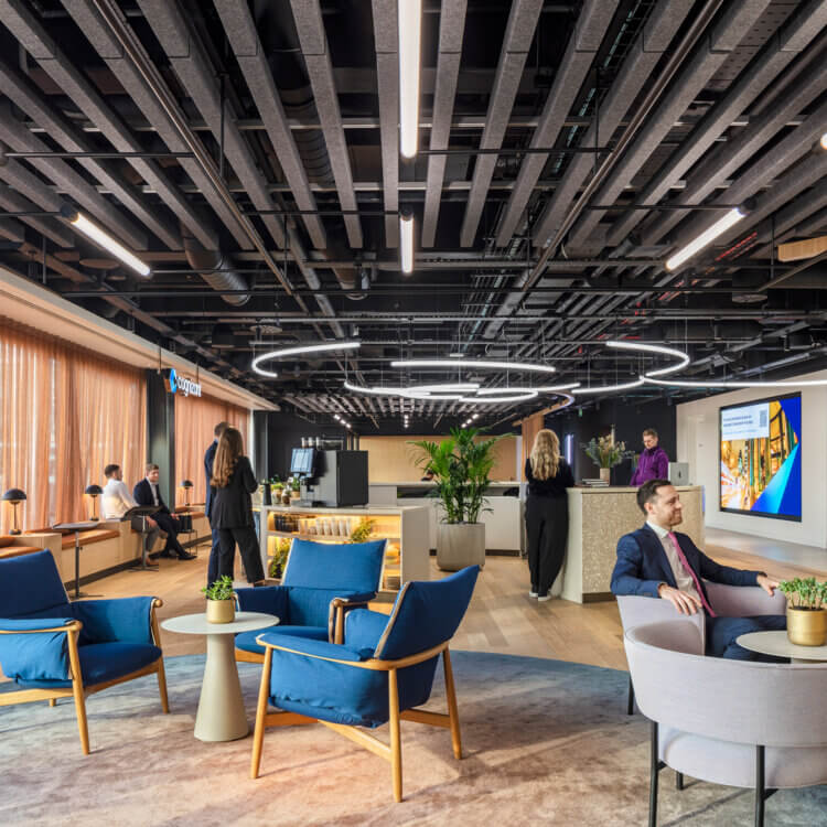 Individuals and small groups of people socialize in an office reception area.