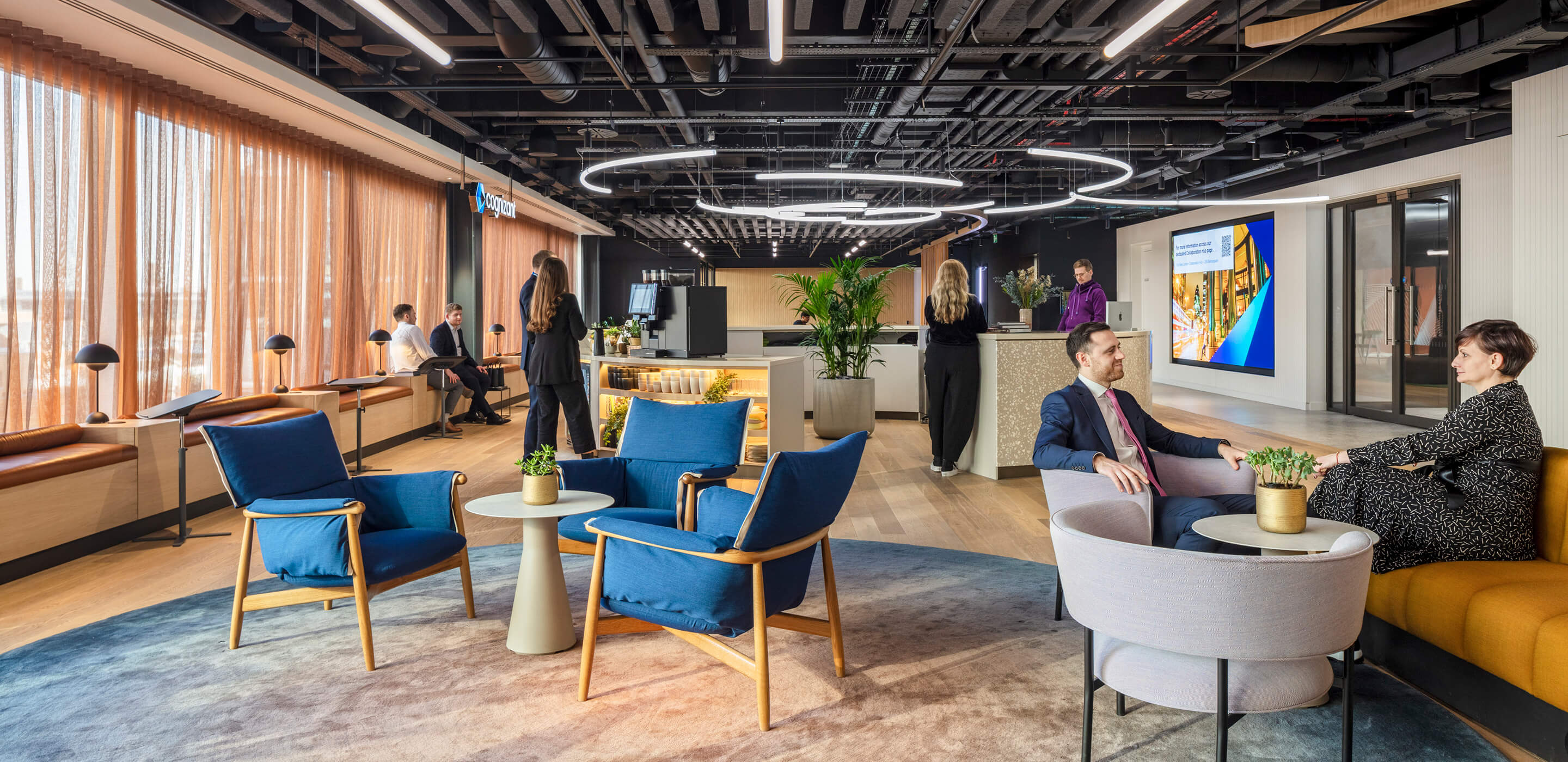 Individuals and small groups of people socialize in an office reception area.