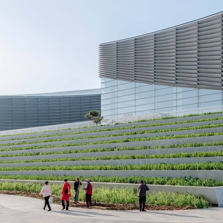 Exterior of building with plaza, landscaping, and people walking by